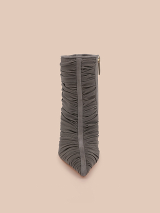 The Fulton Mesh Bootie is a gray, ruched fabric bootie with a pointed toe and a side zipper, showcasing a sleek stiletto-inspired silhouette and photographed against a plain light peach background.