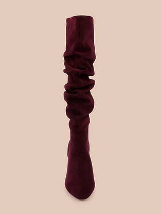 Front view of a single Fletcher Boot in slouchy burgundy suede, featuring a rounded toe and block heel, photographed against a plain beige background—perfect for adding a touch of bohemian chic to any outfit.