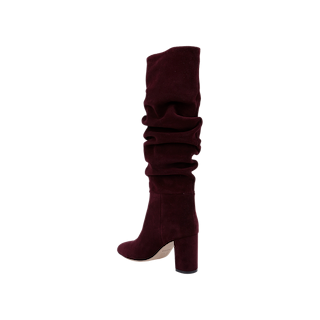 The Fletcher Boot—a knee-high, slouchy suede boot in rich burgundy, featuring a chunky block heel—is displayed on a plain white background, making it the perfect piece to add bohemian chic style to your look.