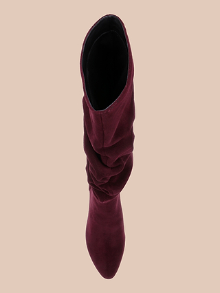 A top view of the Fletcher Boot—a single wine red, slouchy suede boot featuring a pointed toe and block heel—displayed on a beige background, perfect for infusing any outfit with bohemian chic style.