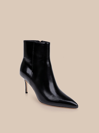The Houston Bootie features a black pointed toe, high stiletto heel, glossy leather finish, and convenient side zipper, showcased on a neutral beige background.
