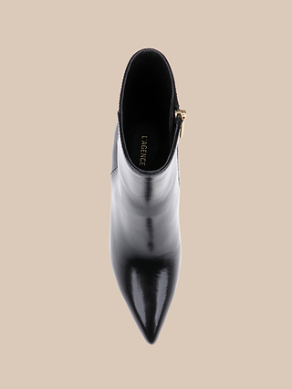 A top view of the Houston Bootie, a black leather bootie featuring a shiny, pointed toe and a side zipper, displayed against a beige background.