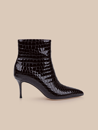 The Houston Bootie, shown in profile against a beige background, features black crocodile-embossed patent leather with a pointed toe and a slim high heel.