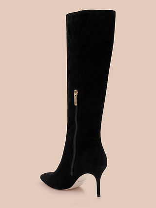 Herald Boot: A black suede knee-high boot featuring a pointed toe, slim stiletto heel, and convenient side zipper, displayed against a plain beige background.