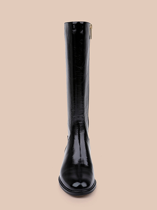 A single Cortland Boot, crafted from shiny black patent leather and designed to reach the knee, is shown standing upright and facing forward against a plain beige background.
