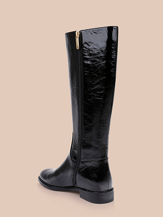 The Cortland Boot, a single tall black knee-high boot featuring a shiny patent leather finish, a side zipper, and a low heel, is displayed against a plain beige background.