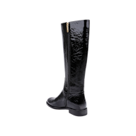 The Cortland Boot is a tall, black patent leather knee-high boot featuring a side zipper and low heel, displayed at an angle against a plain white background.