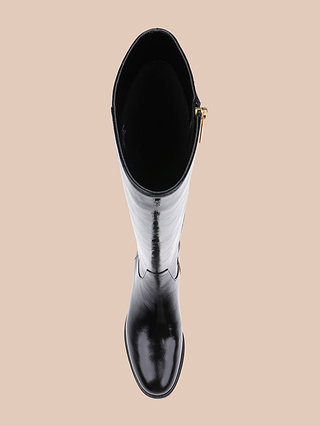 A single Cortland Boot in tall black, viewed from above, highlights its rounded toe, shaft, and gold side zipper against a neutral beige background.