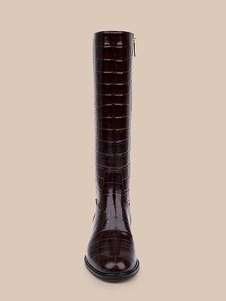 Front view of the Cortland Boot, a tall, dark brown, croc-embossed leather riding boot featuring a rounded toe and a small heel, displayed against a plain beige background.