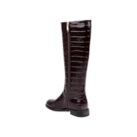 The Cortland Boot is a knee-high design made from dark brown, croc-embossed leather, featuring a low heel and a side zipper, displayed against a plain white background.