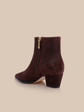 The Vesey Bootie, crafted in mahogany suede with a medium block heel, side zipper adorned with a gold pull, and a slightly pointed toe, is displayed against a plain beige background.