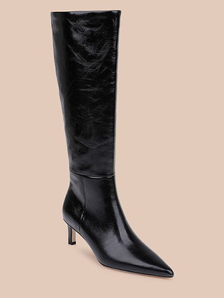 The Baxter Boot is a tall, stylish knee-high boot featuring black patent leather, a pointed toe, and a short stiletto heel, displayed against a beige background.