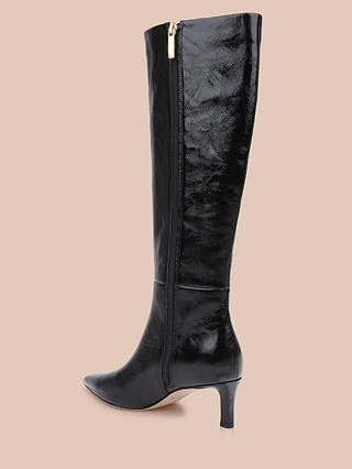 Introducing the Baxter Boot: a single black knee-high boot crafted from shiny patent leather, featuring a pointed toe and convenient side zipper, displayed against a light beige background—highlighting this comfortable and stylish option that’s perfect for any occasion.