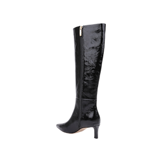 The Baxter Boot is a single black knee-high boot crafted from glossy patent leather, featuring a pointed toe, low heel, and gold side zipper. Displayed on a white background, this comfortable and stylish boot perfectly balances elegance and sophistication.