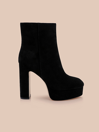 Soho Bootie in black suede, featuring a high platform block heel, displayed in profile against a beige background.