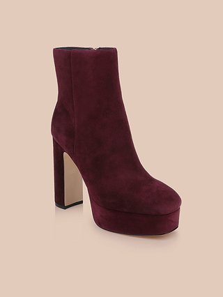The Soho Bootie is a burgundy suede bootie featuring a platform sole and a high block heel, displayed against a plain beige background.