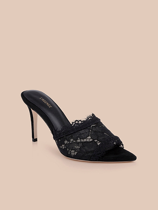 Penn Mule in black lace, designed with a pointed toe and elegant stiletto heel, features an open back and is displayed on a beige background.