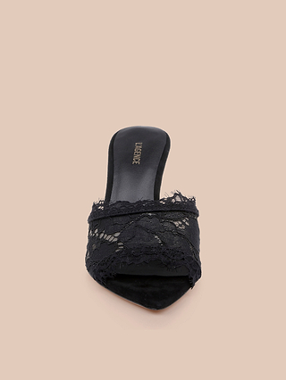The Penn Mule features a pointed toe and elegant stiletto heel, crafted with a delicate black lace overlay, an open back, and the VALENTINE label on the insole, shown against a beige background.