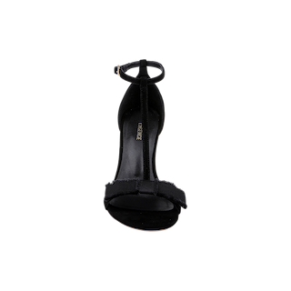 The Lerner Sandal is a black high-heeled T-strap sandal with an ankle strap, featuring a suede upper, front bow detail, and an open toe, shown from the front against a plain white background.