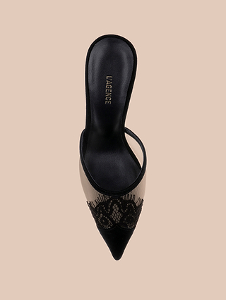 A top-down view of the Semois Mule showcases its black pointed-toe design, featuring delicate lace-capped detailing and a sheer mesh upper against a beige background. “LAGENCE” is printed on the insole, while a sleek black suede heel adds an elevated finish to the elegant silhouette.