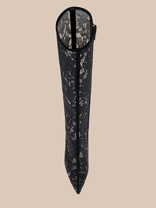 Top view of the Chambers Boot—a tall, pointed-toe black lace boot featuring a stiletto heel and beige inner lining—displayed against a plain beige background.