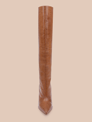 The Lafayette Boot, a tall brown boot made from lizard-embossed leather, stands upright on a light beige background and is photographed from the front with its toe pointing forward.