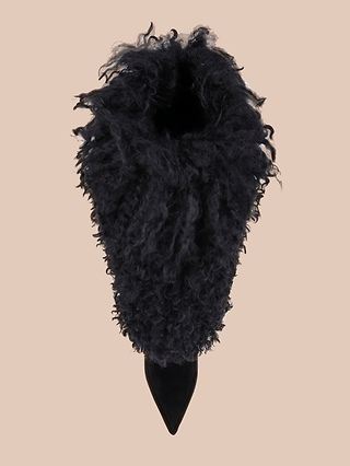 A top-down view of the Sheridan Boot showcases its black, curly, fur-like exterior and pointed toe, reminiscent of plush faux fur boots or a fuzzy mid-calf style, set against a plain beige background.