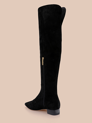 Grand Boot in black suede features a low heel, side zipper, and pointed toe, displayed against a beige background.