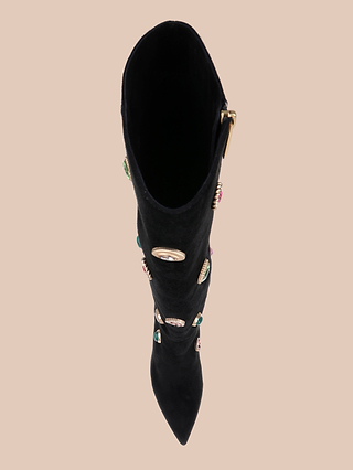 Top view of the Concourse Boot in classic black suede, this luxury statement piece showcases a knee-high silhouette with a pointed toe, embellished with colorful gemstones and a gold buckle on the side, displayed against a plain beige background.