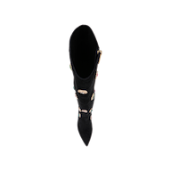 The Concourse Boot, a black pointed-toe design viewed from above, features colorful stones and gold accents running vertically along the front, creating a luxurious statement. The image is set against a plain white background.
