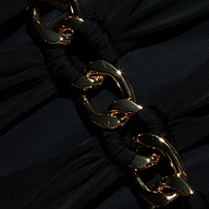 Close-up of shiny gold chain links intertwined with gathered black fabric on the Opus Halter One-Piece Swimsuit, creating an elegant and textured contrast between the metal and cloth—an accent reminiscent of high-end resort swimwear.