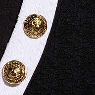 Close-up of the Laguna Rash Guard in black and white, featuring water-safe bouclé fabric and two gold eagle-embossed buttons for a stylish, polo-inspired look.