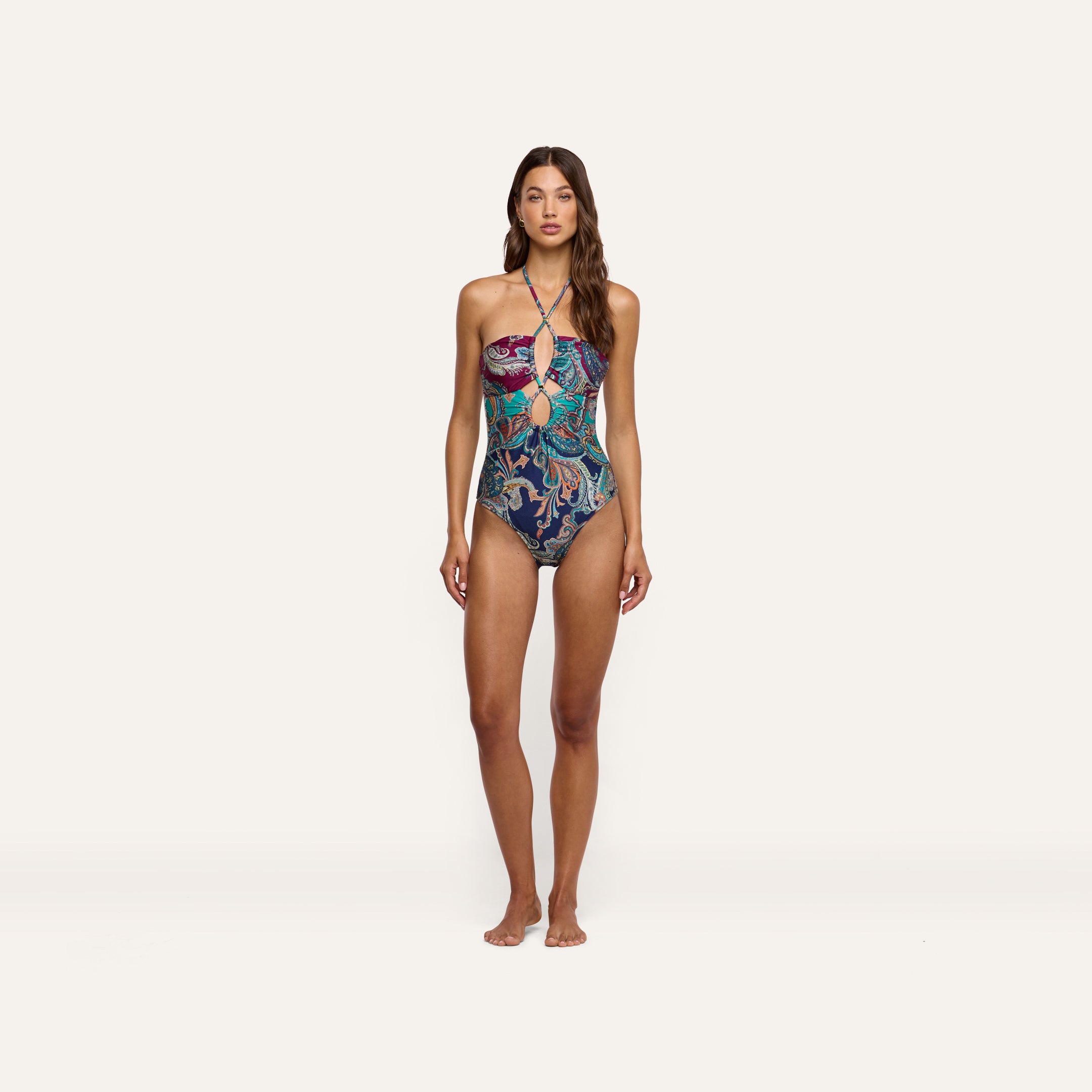A woman wearing a Shiva One-Piece Swimsuit featuring a paisley print and a front cutout.