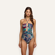 A woman wears a Shiva One-Piece Swimsuit, a UPF 50, halter-style one-piece featuring a colorful paisley pattern and a cutout detail at the chest.