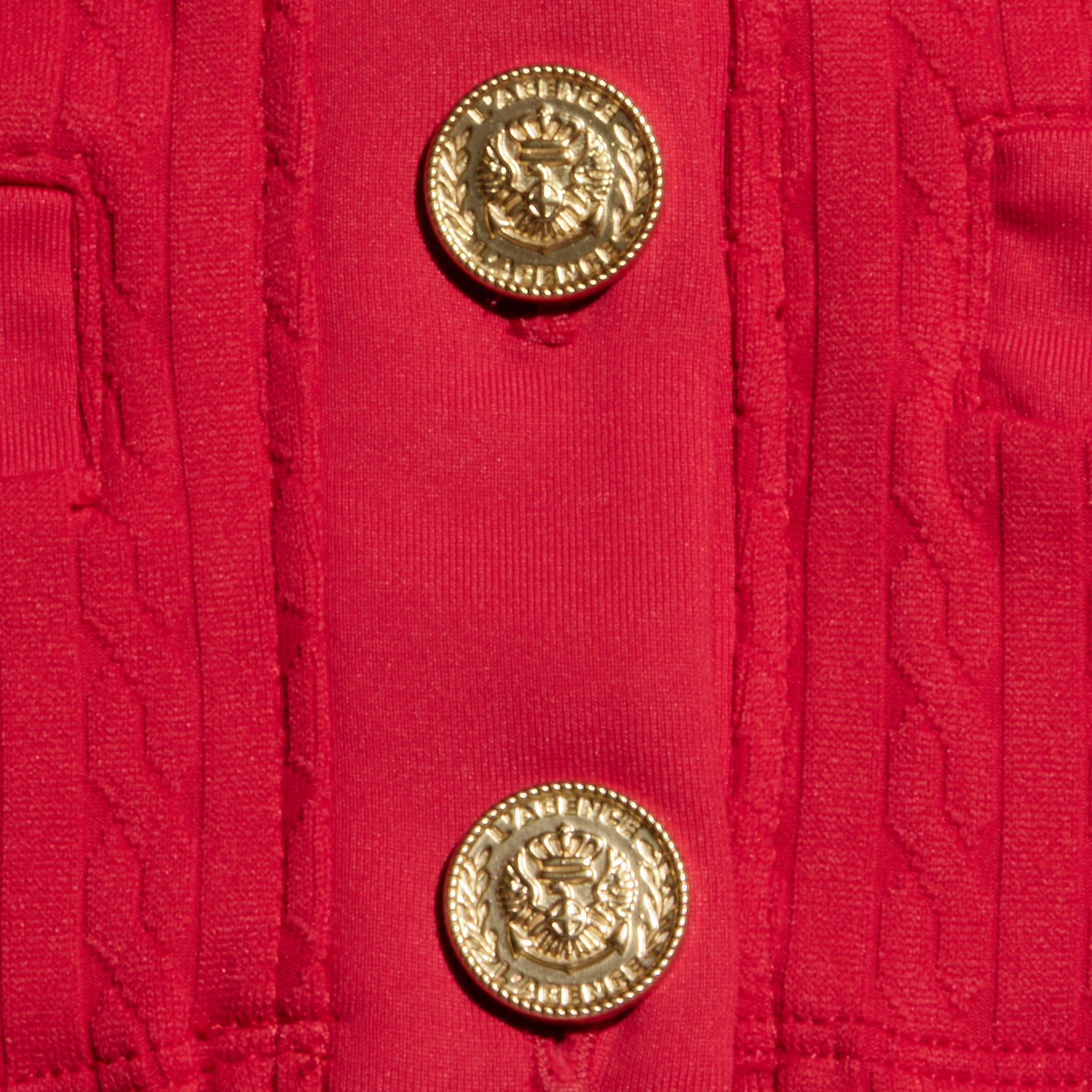 Close-up of the Adaline Cardigan Cover-Up in red, showcasing two gold decorative buttons embossed with eagles encircled by laurel wreaths. The vertically aligned buttons and textured stitching highlight the refined craftsmanship of this stylish swim cover-up.