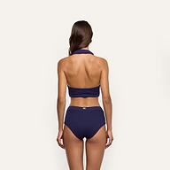 Back view of a person wearing a navy blue Catalina Bikini Top in a cable knit design with a collared halter silhouette.