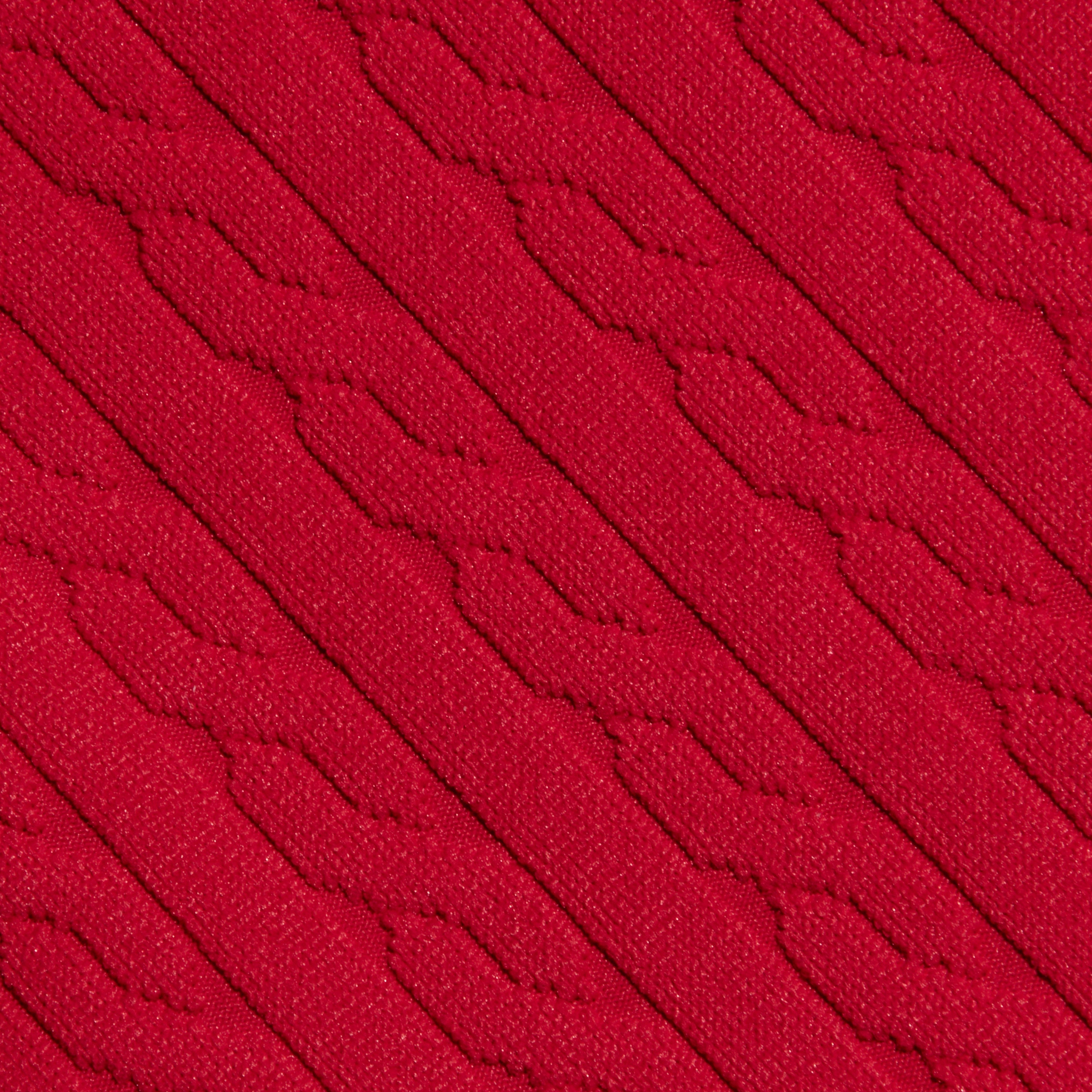 Close-up of the Jean Bikini Bottom’s red textured swim fabric, showcasing diagonal, raised patterns and a knit-like appearance. The design features repeating geometric shapes for a tactile look.