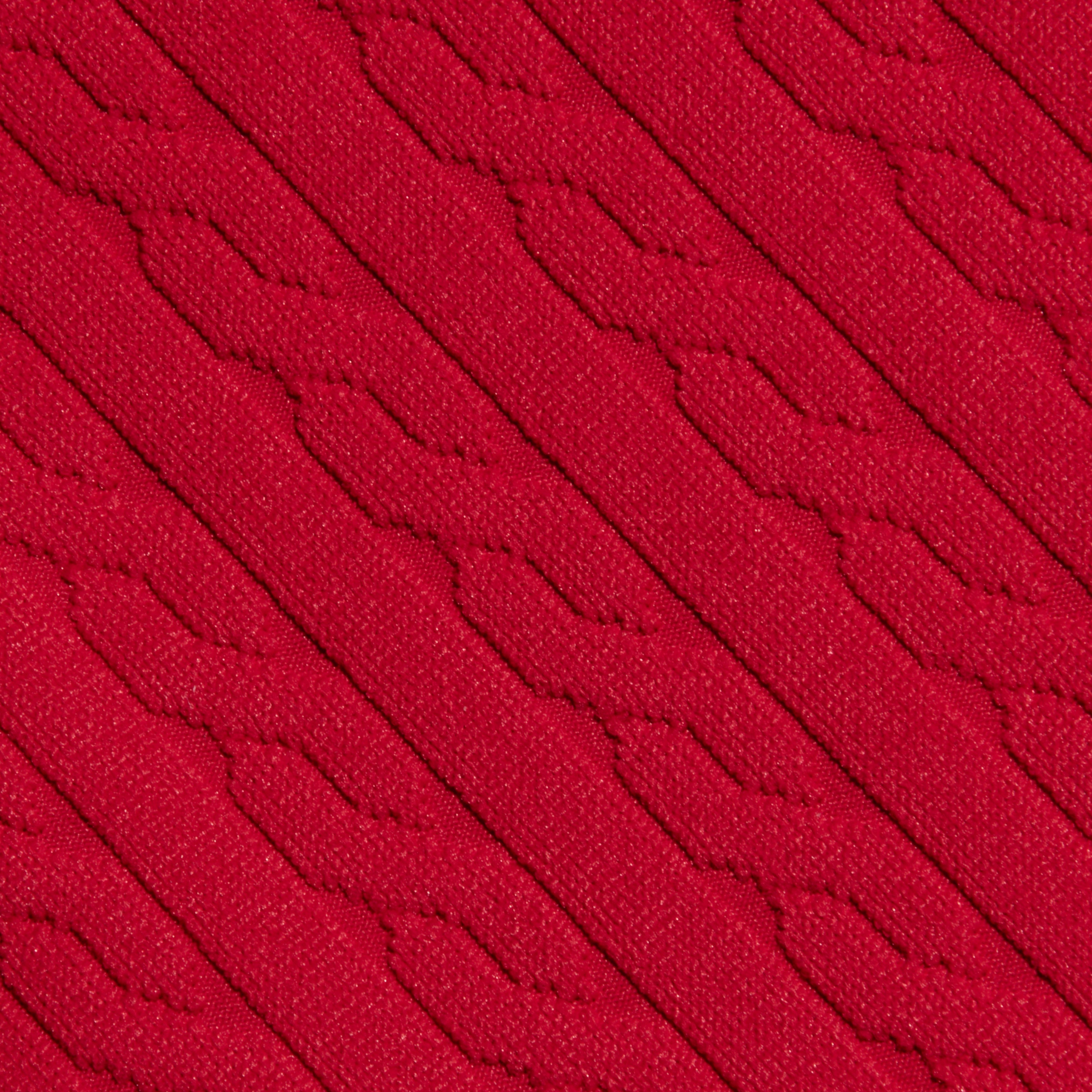 Close-up of the Jean Bikini Bottom’s red textured swim fabric, showcasing diagonal, raised patterns and a knit-like appearance. The design features repeating geometric shapes for a tactile look.