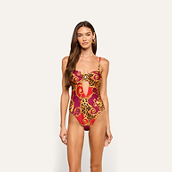 A woman stands against a plain light background, wearing the Emilia Bandeau One-Piece Swimsuit—a red and yellow patterned bandeau with a keyhole cutout, perfect for resort swimwear.