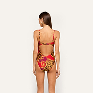 A woman with long brown hair models the Emilia Bandeau One-Piece Swimsuit, which features a red, gold, and leopard print design and a bandeau silhouette with a cutout back. She is posed facing away from the camera against an off-white background.