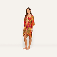 A woman stands barefoot against a plain white background wearing a vibrant red and yellow leopard print bikini paired with the Kara Cover-Up Kimono and accessorized with a gold chain belt.