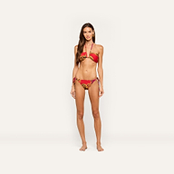 A woman stands barefoot wearing the Getty Bandeau Top, a red and leopard print bikini with gold accents, posing against a plain, light background.