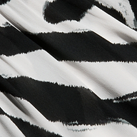 Close-up of black and white striped fabric with a wavy, irregular pattern resembling zebra print. The slightly textured material, shown with visible folds and creases, is featured in the Sara Maxi Cover-Up Dress—an ideal choice for a stylish zebra print cover-up.