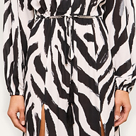 Close-up of a person wearing the Sara Maxi Cover-Up Dress, featuring a black and white zebra print with a thin waist belt and tasseled cords, highlighting the dress’s unique pattern and details.