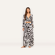 A woman stands facing forward against a plain light background, wearing the Geraldine Cover-Up Pant in a zebra-print matching set with a long-sleeve crop top and wide-leg resort wear pants.