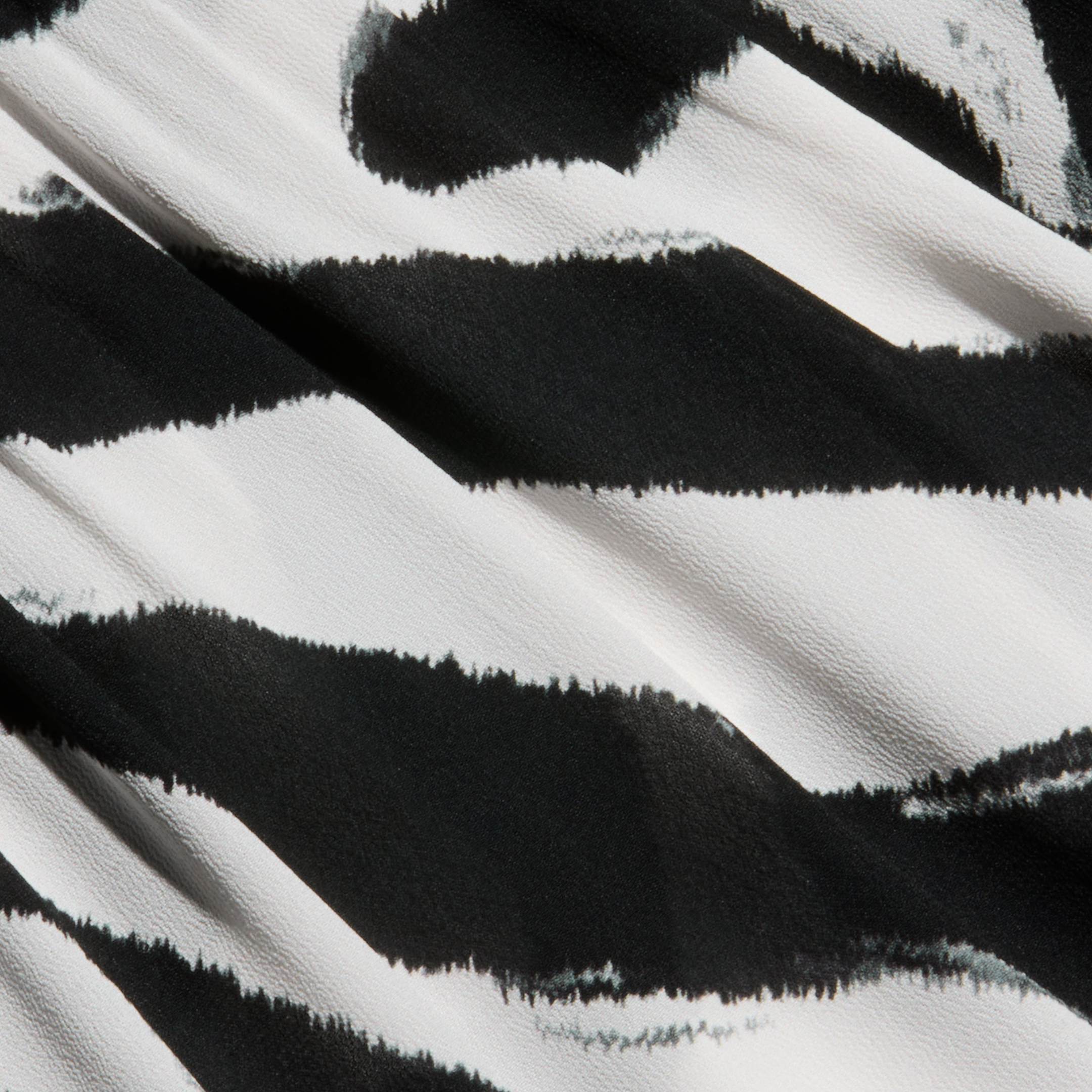 Close-up of the Geraldine Cover-Up Pant in a black and white zebra print with a striking stripe pattern. The textured fabric highlights wavy, irregular lines as light and shadow play across the surface.