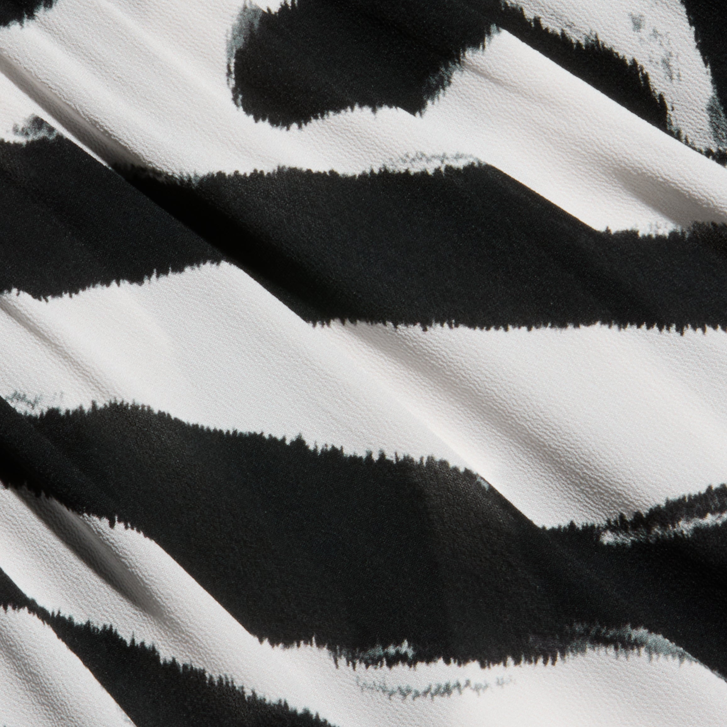 Close-up of the Geraldine Cover-Up Pant in a black and white zebra print with a striking stripe pattern. The textured fabric highlights wavy, irregular lines as light and shadow play across the surface.