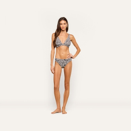 A woman with long brown hair stands barefoot and facing forward against a plain light background, wearing the Lexie Bikini Top in a zebra print, with a neutral expression.