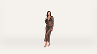 A woman stands barefoot, wearing a sheer black mesh dress over black lingerie, set against a plain white background.
