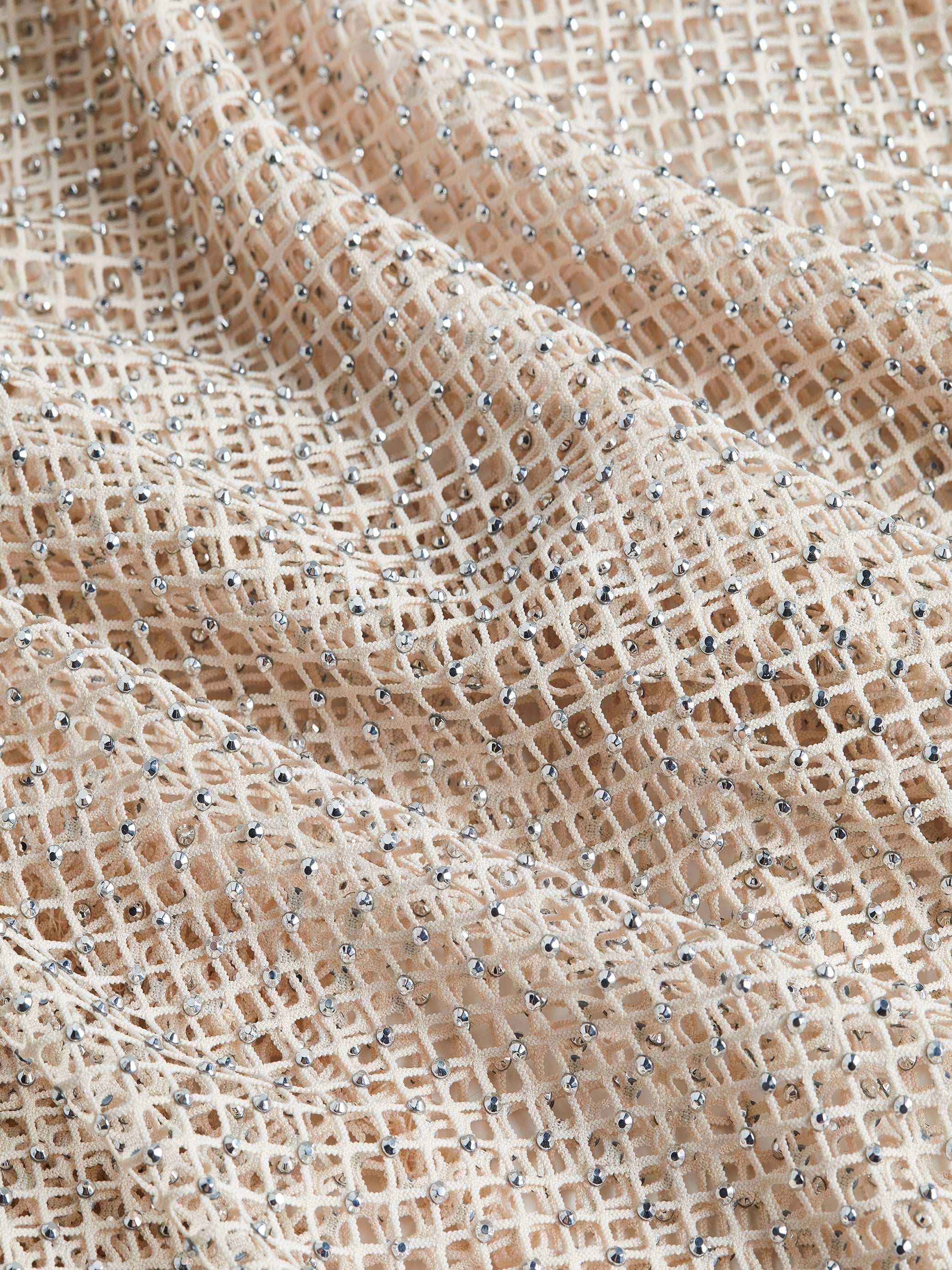 Close-up of the Sara Mesh Cover-Up Dress, featuring beige mesh fabric with a delicate grid pattern adorned with shimmering silver sequins. The soft material drapes naturally, creating gentle folds and an elegant textured look—ideal for crafting a stunning mesh maxi dress or wearing as a sophisticated beach cover-up.